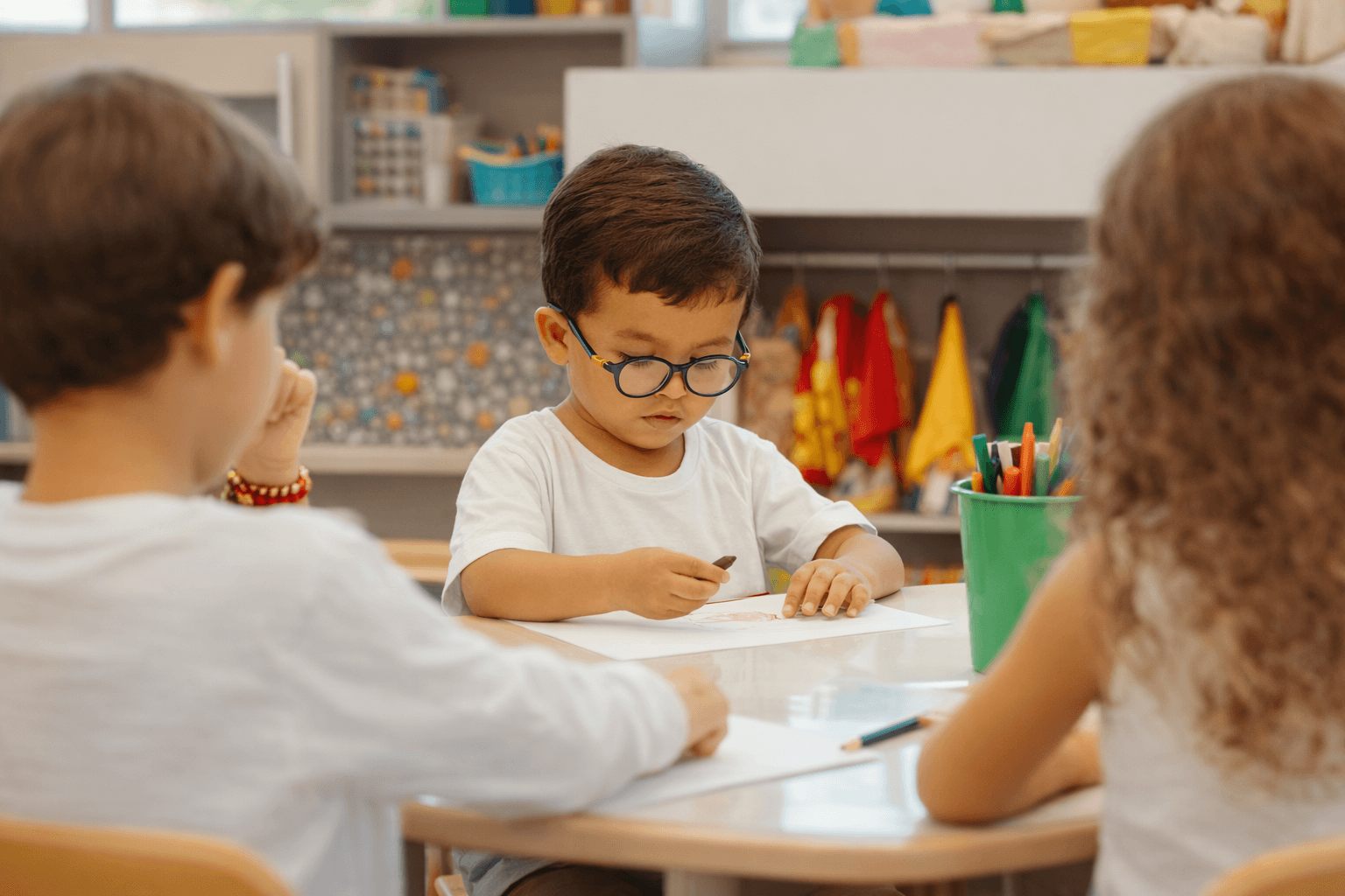 Jeune enfant concentré en train de dessiner dans une salle de classe.